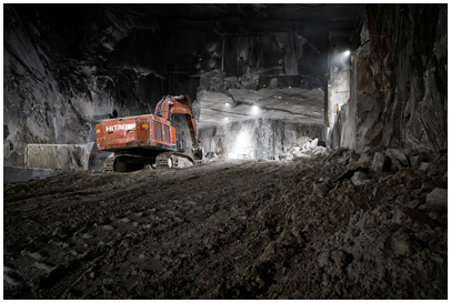 Escavatrice nella cava di marmo dentro la montagna